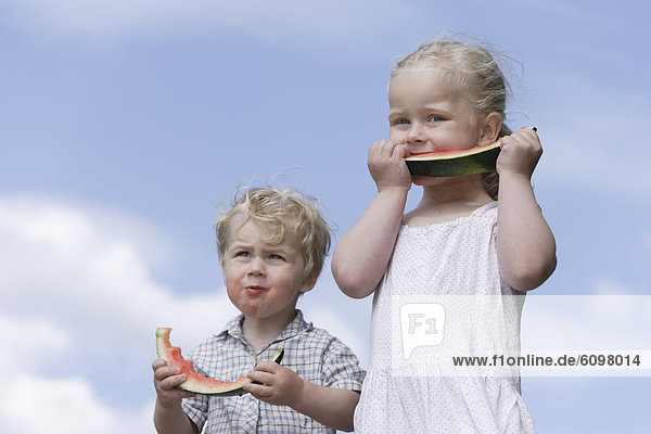 Girl and boy eating watermelon