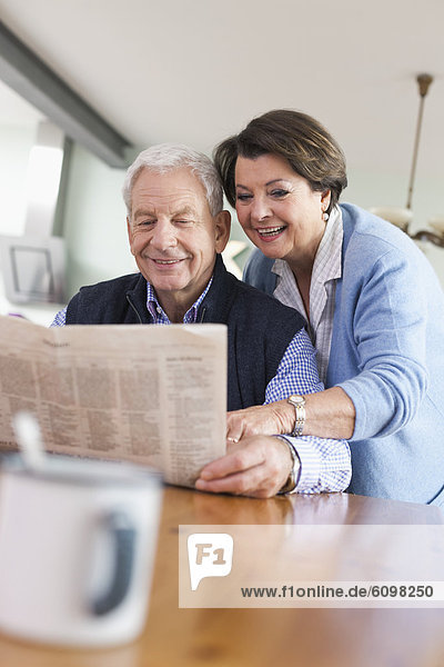 Senior man and woman reading newspaper  smiling