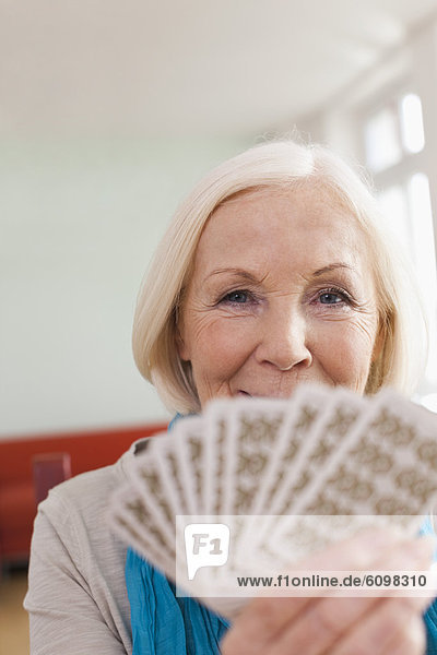 Senior woman playing cards  smiling  portrait