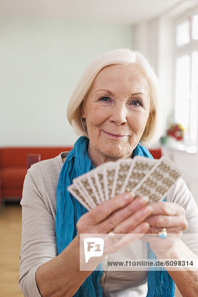 Seniorin beim Kartenspielen  lächelnd  Portrait