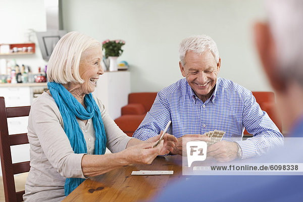 Senior men and woman playing cards  smiling