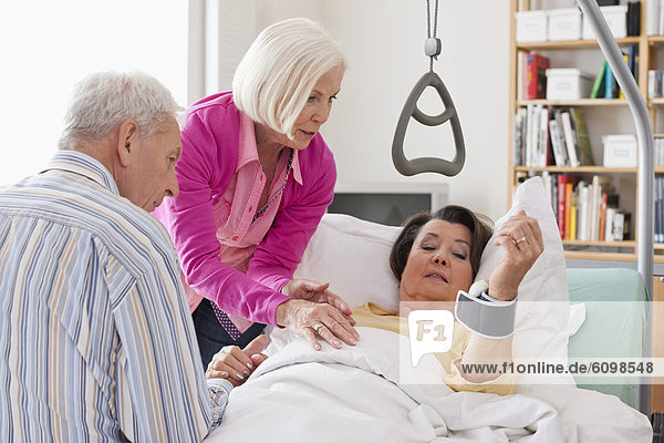 Senior woman lying on bed  man and woman sitting beside