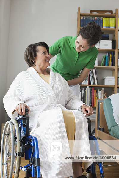 Senior woman sitting on wheelchair  mid adult woman standing beside