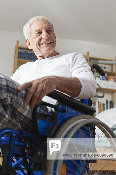 Älterer Mann im Rollstuhl sitzend  lächelnd