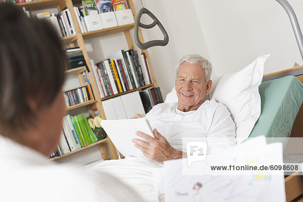 Senior man lying on medical bed and drawing