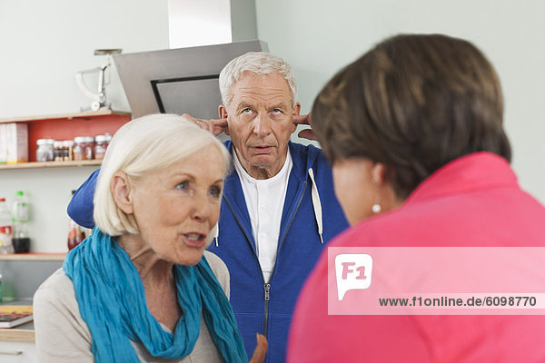 Seniorinnen diskutieren  Mann mit Ohren im Hintergrund