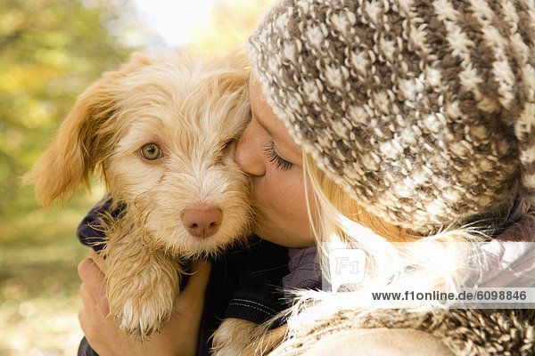 Österreich  Junge Frau küsst Hund im Herbst  Nahaufnahme