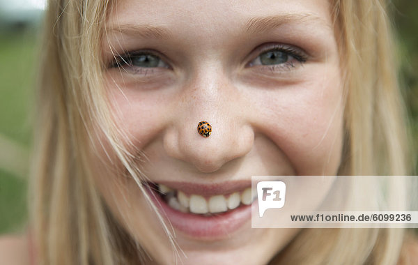 Österreich  Teenagermädchen mit Marienkäfer auf der Nase  lächelnd  Portrait