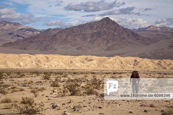 A young man backpacks through the Confidence Hills in Death Valley Nation Park  California.
