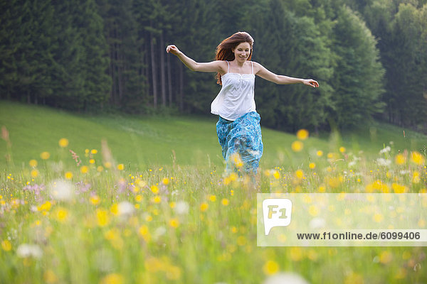 Österreich  Junge Frau beim Laufen im Blumenfeld