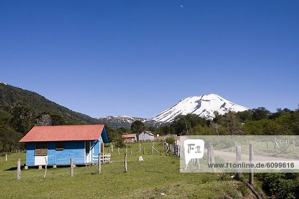Volcan Lonquimay and a blue farm house in the Andes mountains of Chile