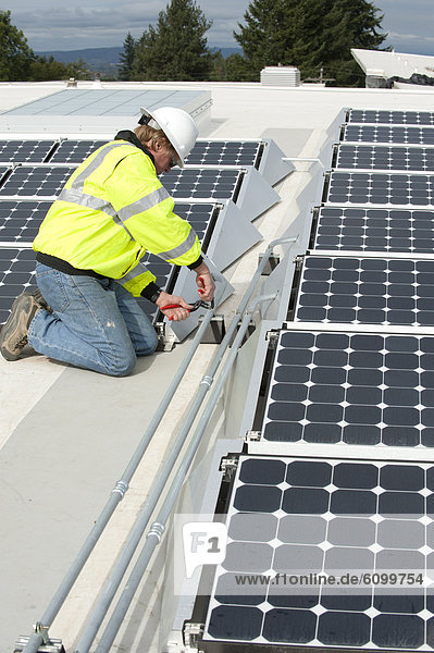 Green energy technician adjusts photovoltaic panels on a roof