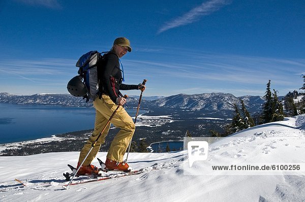 A female skier skins up Mount Tallac with Lake Tahoe in background  CA.
