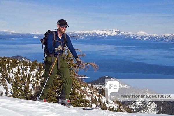 A male skier skins up Mount Tallac with Lake Tahoe in the background  CA.