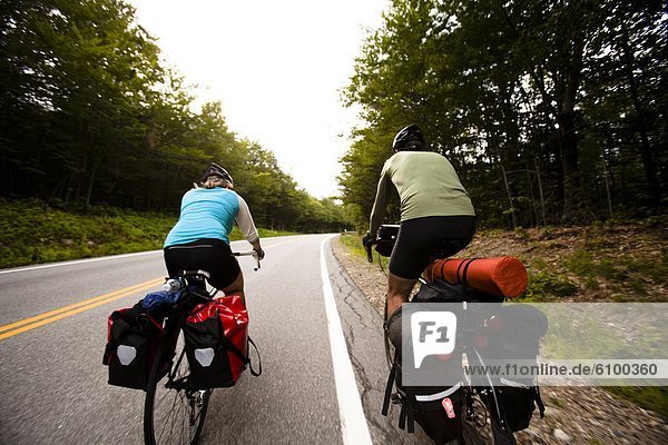 During a cycling tour a female and male cyclist climb up the Kancamagus Highway.