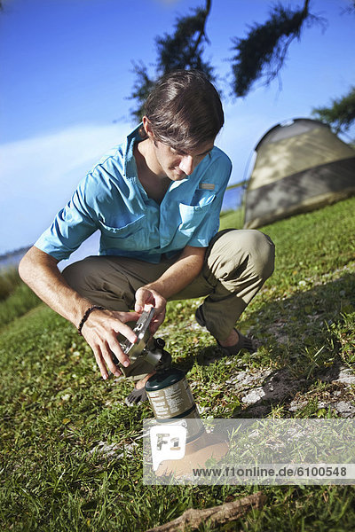 Young man prepares a gas burner at a campsite on the banks of Shelby Lakes in Gulf Shores Alabama.