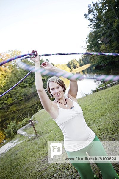 A mid adult woman twirls two hula hoops over head while exercising in Chelsea  Alabama.++