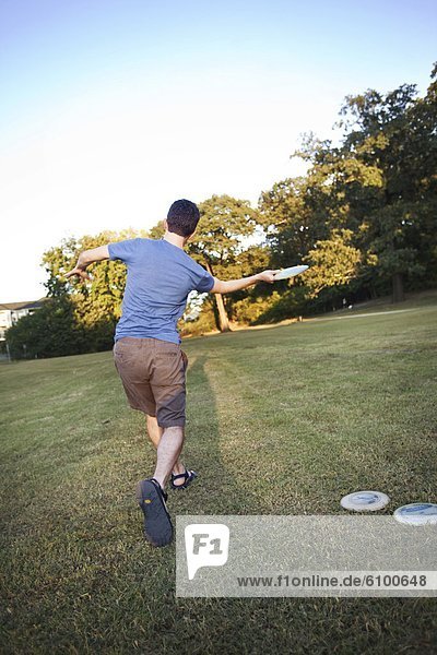 A man makes a forehanded throw playing disc golf.