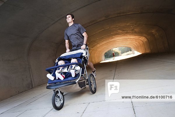 A man exiting a tunnel  running with his twin boys in a stroller in Helena  Alabama.