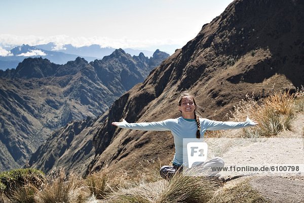 A young woman enjoys a beautiful moment and breathes in the fresh air while on Dead Woman's Pass  Inca Trail.