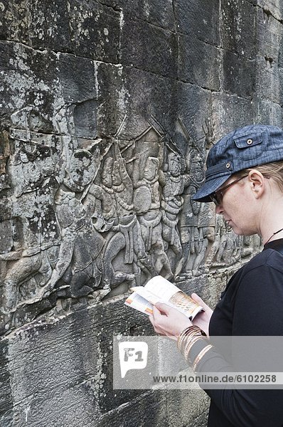 Woman traveller reading a guidebook at Angkor Wat  Cambodia.