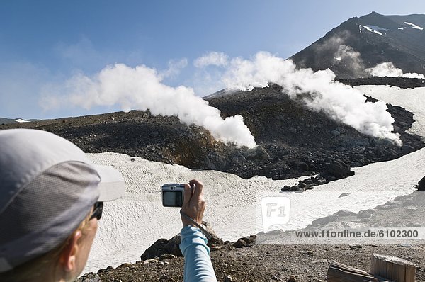Woman photographing steaming fumaroles  Mt Asahi-dake  Hokkaido  Japan