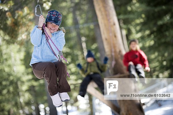 A girl ziplines over the snow while two friends watch in Lake Tahoe  California.