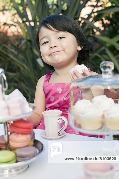 A young girl eating a marshmallow at a tea party in Los Angeles  California.