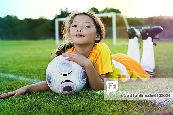 A young girl posing with her soccer ball on a soccer field in Los Angeles  California.