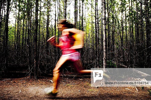 Woman jogging through a thick forest.