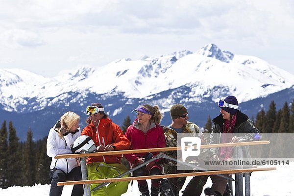 A large group of friends smile and laugh while enjoying a beautiful skiing day in Colorado.