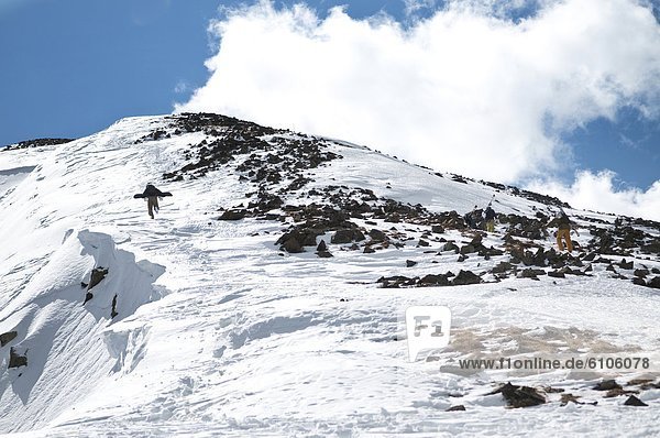 An extreme snowboarder climbs to Kachina Peak's summit at Taos Ski Valley  New Mexico.