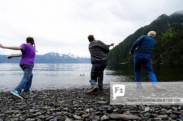 Three men have a rock-skipping contest on Fox Island  Alaska.
