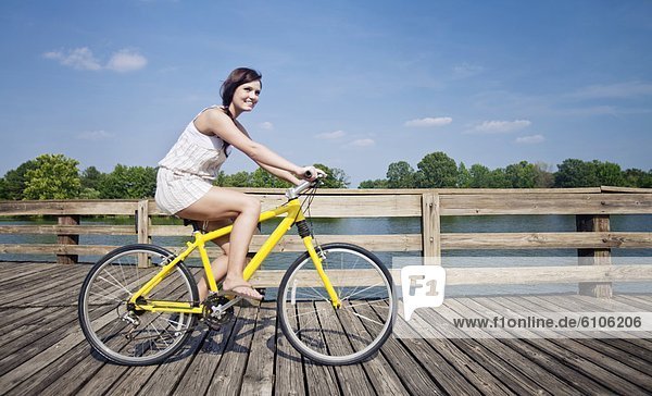 A young girl rides a yellow bike down a pier.