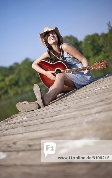 junge Frau junge Frauen sitzend Kai Gitarre spielen