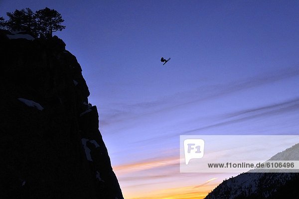 Pro skier Josh Daiek performs a front flip at sunset while ski BASE jumping off of Lovers Leap in Strawberry  CA.