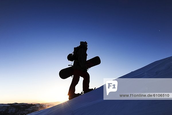 A silhouette of a snowboarder snowshoeing at sunrise in the Sierra Nevada near Lake Tahoe  California.