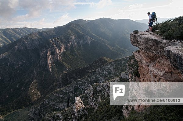 A backpacker peers over a ledge into McKittrick Canyon at Guadalupe National Park.