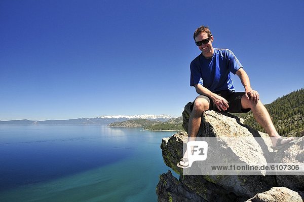 A man relaxes on a boulder overlooking Lake Tahoe in the summer  Nevada.