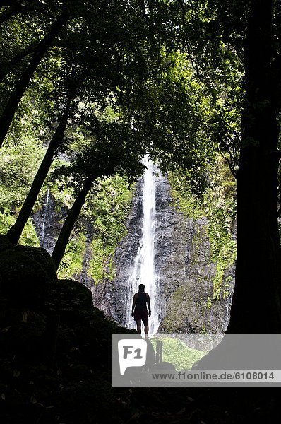Woman standing in front of a waterfall  Faarumai Waterfall  Tahiti.