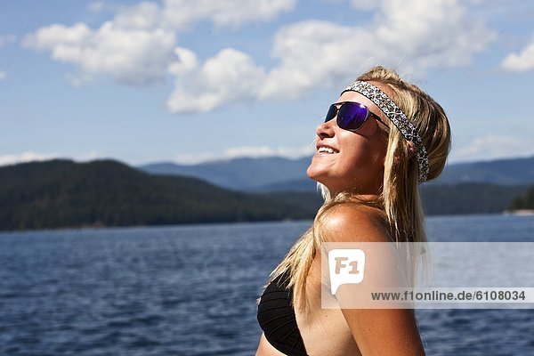 A athletic young woman smiles while subathing next to a lake in Idaho.