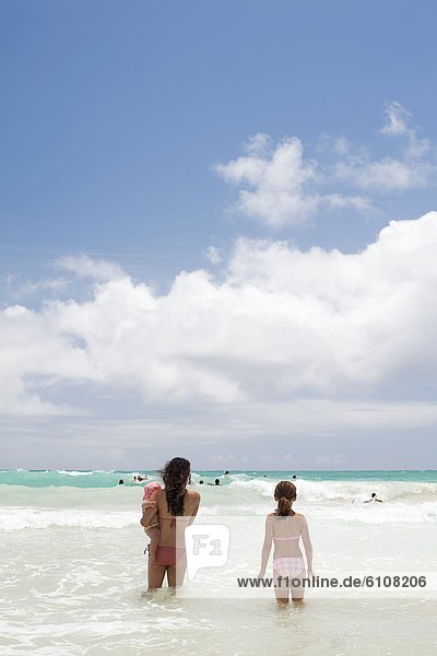 Two girls and a baby going into the sea in Kailua  Hawaii.