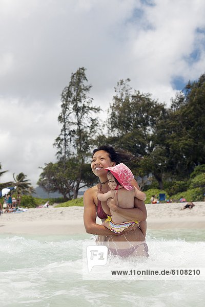 A mother carrying her baby at the beach in Kailua  Hawaii.