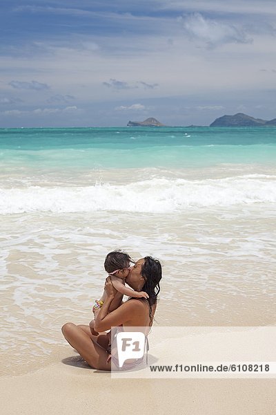 A mother giving her baby a kiss at the beach in Waimanalo  Hawaii.