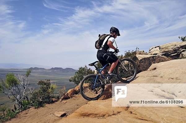 A man mountain bikes on the South Rim Trail of Gooseberry Mesa in southern Utah.