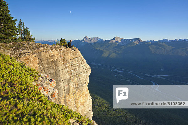 A hiker sits on a cliff edge  Banff National Park  Alberta  Canada.