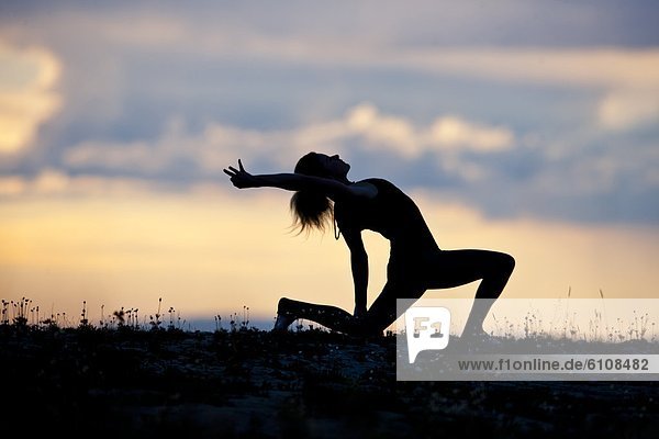 A woman performs a Hatha Yoga pose on a mountain top.
