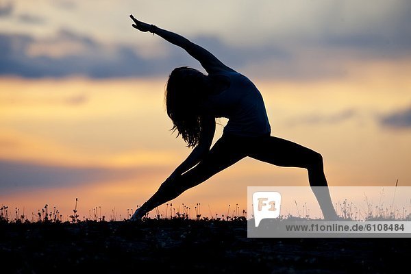 A woman performs a Hatha Yoga pose on a mountain top.