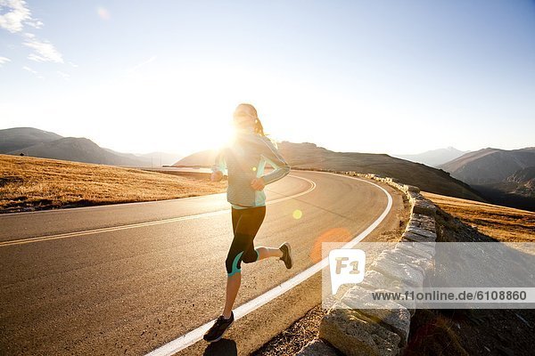 An athletic woman runs along Trail Ridge Road (12 183 feet) near its apex at sunrise  Rocky Mountain National Park  Colorado.