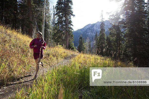 A woman trail running through the woods of Solitude ski resort.